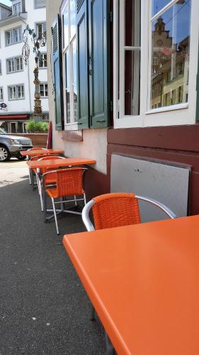 a row of orange tables and chairs in front of a building at Spalenbrunnen Hotel & Restaurant Basel City Center in Basel