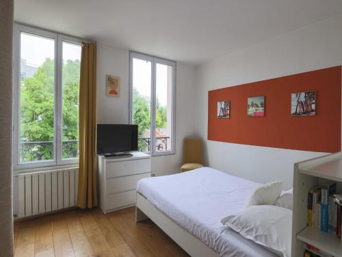 a bedroom with a bed and a tv and windows at House with garden 4BR 10P near Paris in Le Kremlin-Bicêtre