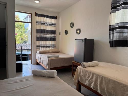 a room with two beds and a refrigerator at Casa Rockot in Puerto Escondido