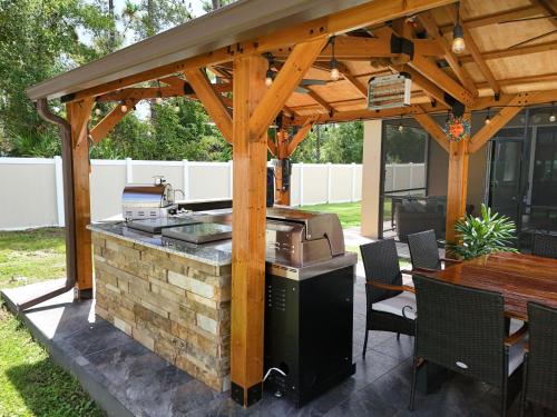 a barbecue under a wooden pavilion with a table at Serenity Escape in Palm Coast