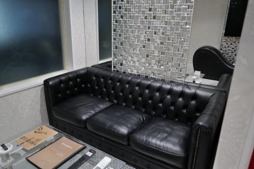 a black leather couch sitting in a room at HOTELO OTONA no ASOBIBA in Yosano