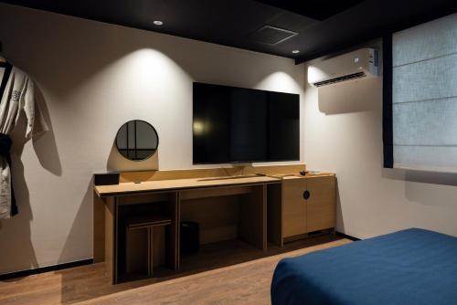 a bedroom with a desk with a television on a wall at Mitasuya Ryokan Hotel by Aank Cheonan in Cheonan