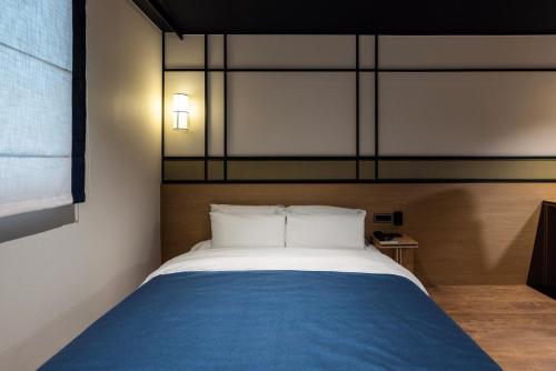 a bedroom with a bed with a blue blanket at Mitasuya Ryokan Hotel by Aank Cheonan in Cheonan