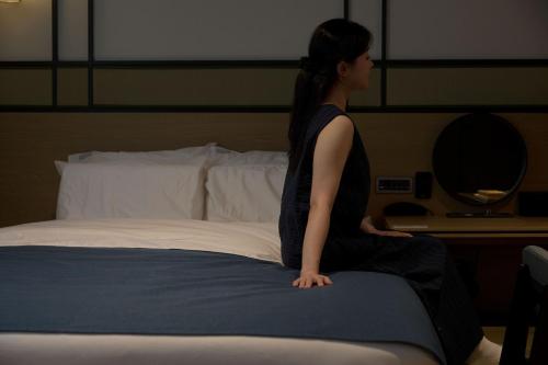 a woman sitting on top of a bed at Mitasuya Ryokan Hotel by Aank Cheonan in Cheonan