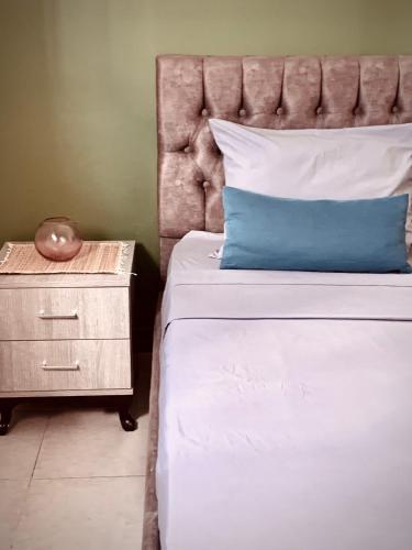 a bed with a blue pillow and a night stand at Havre de paix au centre de la marsa in La Marsa