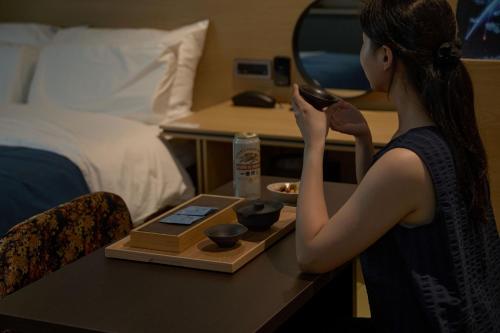 a woman looking at herself in a mirror in a hotel room at Mitasuya Ryokan Hotel by Aank Cheonan in Cheonan