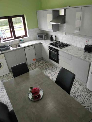 a kitchen with a table with a bowl of flowers on it at Orchard Brooke Cottage in Downpatrick