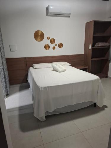 a bedroom with a bed with a white blanket andcoins on the wall at Pousada Chalés da Serra in Cuité