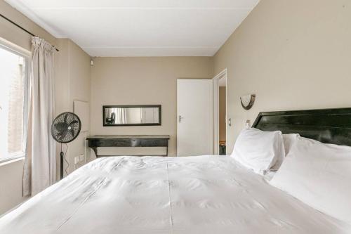 Una cama blanca grande en un dormitorio con ventana. en Peaceful & Cozy Apartment, en Johannesburgo