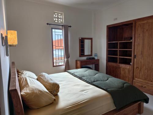 a bedroom with a large bed with a window and a window at Ayuna Guest House in Darmasaba