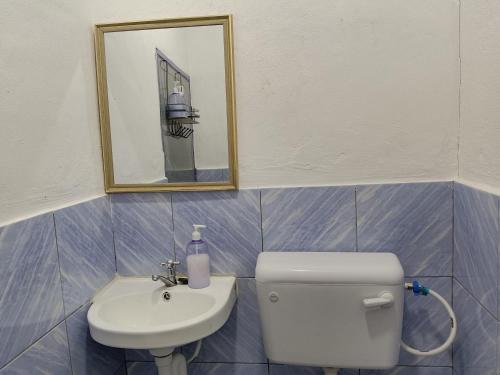 a bathroom with a toilet and a sink and a mirror at Homestay Impian Bapa in Semporna