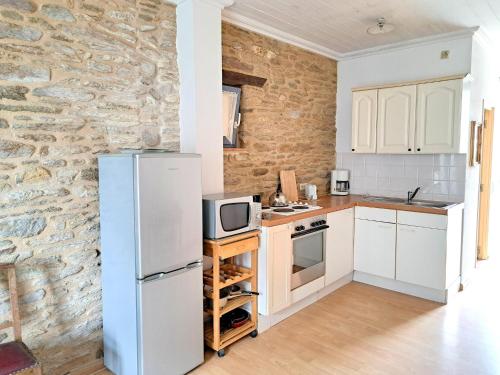 - une cuisine avec des appareils blancs et un mur en pierre dans l'établissement First floor studio near the beach, au Pouldu