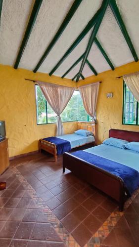 two beds in a room with yellow walls and windows at Finca Villa Tere in Fusagasuga