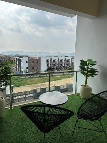 Un balcón con 2 sillas, una mesa y una planta en Cozy 2BR Near Banex Plaza Fast WiFi, en Mobushipe