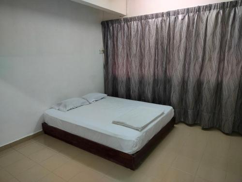 a small bed in a room with a curtain at Travellers Space 2 in Kuantan