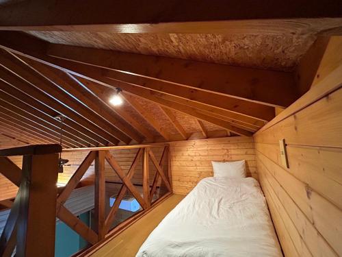 un piccolo letto in una camera con soffitto in legno di 草枕 -kusamakura- private stay a Tomakomai