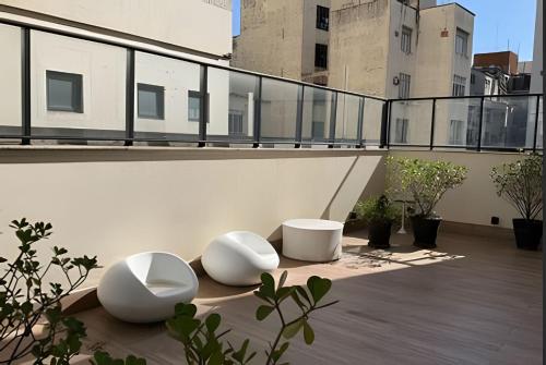 einen Balkon mit zwei weißen Stühlen auf einem Gebäude in der Unterkunft Studio moderno próximo ao metrô Republica in São Paulo