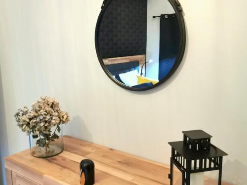 a mirror on the wall above a table with a vase of flowers at Gîte de Charme avec Terrasse Privative et Grand Jardin près du Parc Le Pal - FR-1-489-339 in Thiel-sur-Acolin