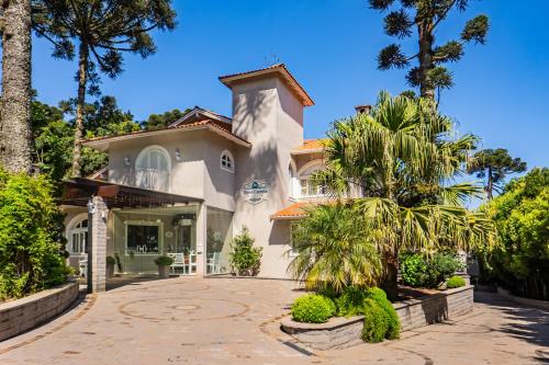 a large white house with palm trees and a driveway at Doce Canela - Pousada de Charme in Canela