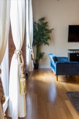 a living room with white curtains and a blue couch at Top Floor Loft in Downtown Indianapolis in Indianapolis