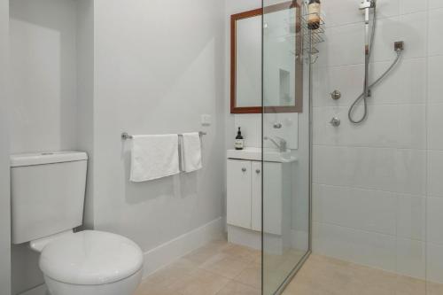 a white bathroom with a shower and a toilet at Follow The Sun in Smiths Lake