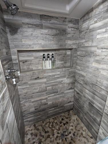 a bathroom with a shower with three bottles at The Nest Cottage with Hot Tub in Downtown Manitou Springs in Manitou Springs