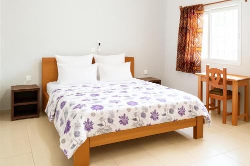 a bedroom with a bed and a desk and a window at La Maison Du Voyageur in Kribi