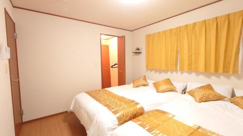 a bedroom with two beds with white sheets and gold pillows at 22minutes by car to Nagoya Station 2parking 