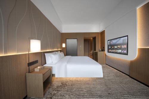 a hotel room with a large bed and a flat screen tv at Guangzhou Huayu Wanfu Hotel-Free Shuttle Bus to Canton Fair Complex During Canton Fair Period in Guangzhou