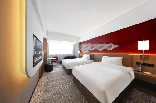 a hotel room with two beds and a red wall at Guangzhou Huayu Wanfu Hotel-Free Shuttle Bus to Canton Fair Complex During Canton Fair Period in Guangzhou