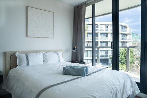 a bedroom with a white bed with a large window at Harbour Hideaway in the CBD in Sydney