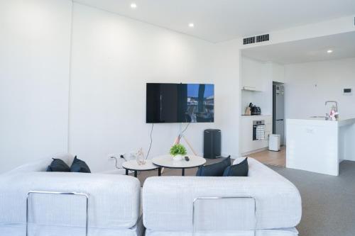a living room with two white chairs and a table at Harbour Hideaway in the CBD in Sydney