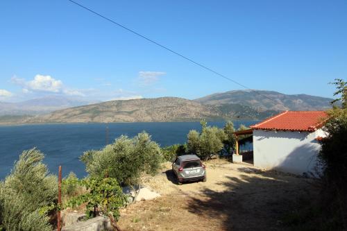 a car parked next to a house next to the water at Lakeview Villa Nardi in Ksamil