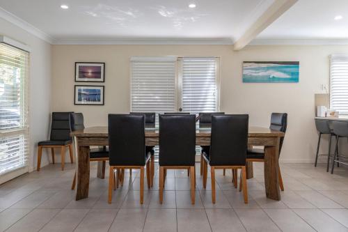 a dining room with a wooden table and chairs at Amaroo Sunset Lodge in Smiths Lake