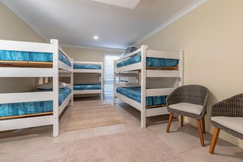 a room with four bunk beds and a table and chairs at Amaroo Sunset Lodge in Smiths Lake