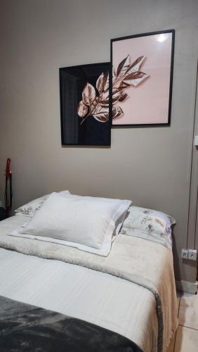 a white bed with two pictures on the wall at Chalé Veraneio-Itú-SP Vista para o lago Camping Carrion in Itu