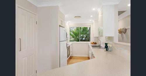 a white kitchen with white counters and a window at Lakeside in Budgewoi