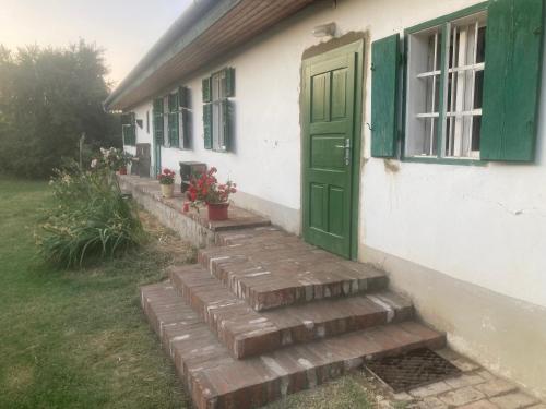 a house with a green door and stairs outside at Erdősmecskei sváb vendégházak és Jurtaszállás in Erdősmecske