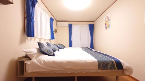a small bedroom with a bed with blue curtains at 22minutes by car to Nagoya Station 2parking 