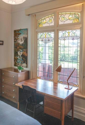 an office with a wooden desk and two windows at Art House in Melbourne