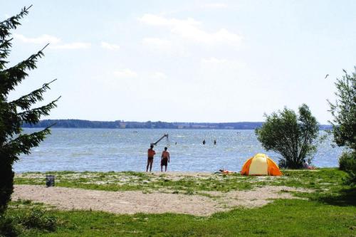 two people standing on a beach next to a tent at Cottages at the Kummerower See in Verchen in Verchen