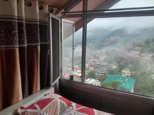 a bedroom window with a view of a city at Aashiyana Studio Homestay in Solan
