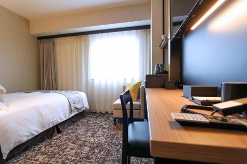 a hotel room with a bed and a desk with a computer at Best Western Plus Nagoya Sakae in Nagoya