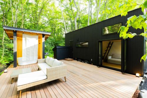 a black house with a white couch on a wooden deck at Morinest 北軽井沢 in Tsumagoi