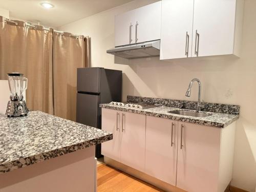 Una cocina con gabinetes blancos y un refrigerador negro. en Frida my Loft, en Ciudad de México