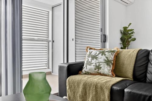 a living room with a black couch and a green vase at Modern Coastal Escape in the Heart of Rockingham in Rockingham