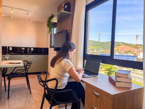 a woman sitting at a desk with a laptop at Apto perto da FIP, Stop Shop in Brusque