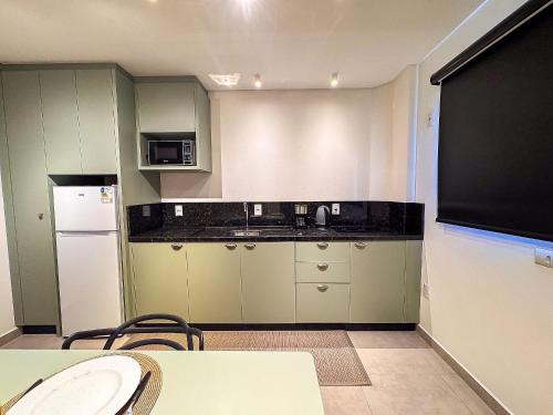 a kitchen with green cabinets and a black counter top at Apto perto da FIP, Stop Shop in Brusque