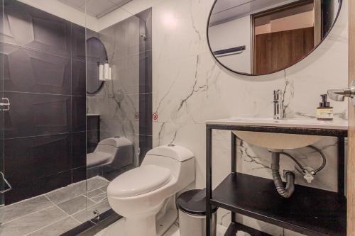 a bathroom with a toilet and a sink and a mirror at Soy Local Parque La 93 in Bogotá