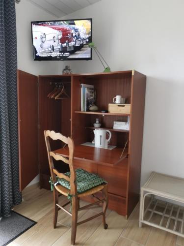a desk with a chair and a tv on a wall at Le moulin de La Retardière in Orvault